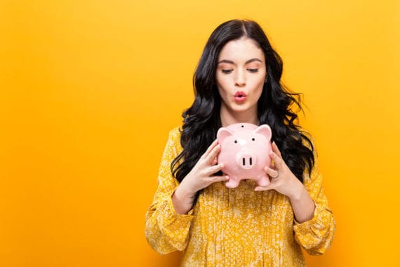Young woman with a piggy bank on a yellow background
